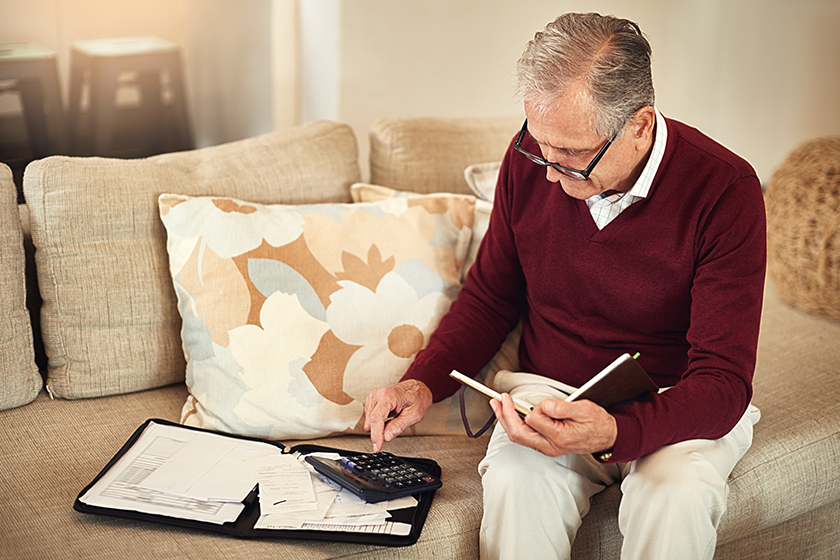 Life without a paycheck can be scary, not for him. a senior man working out a budget while sitting on the living room sofa 